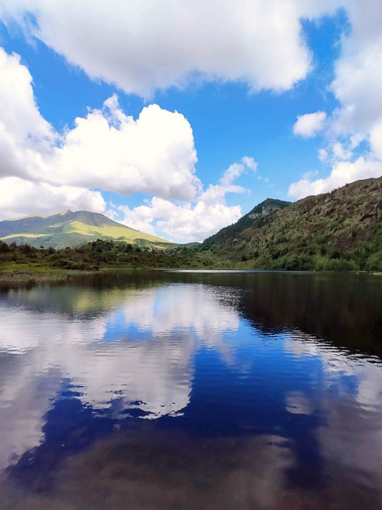 Des nuages se reflètent sur un étang de montagne en été