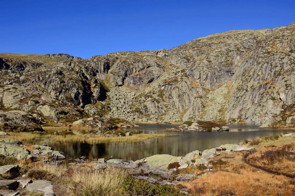 Etang d'Arbu à l'automne, la montagne derrière et des herbes jaunes / orangées