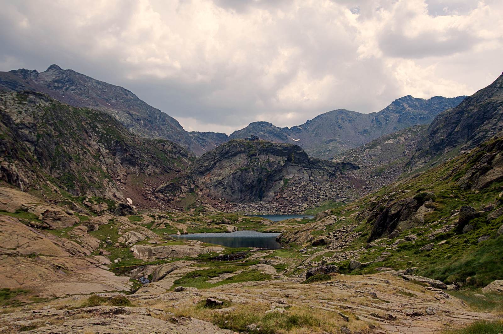 Etang de montagne entouré de roche, on, entraperçoit le refuge qui le surplombe